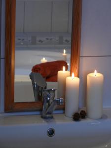 two candles sitting on a bathroom sink in front of a mirror at Domek Kozacki in Łukowe