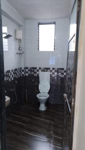 a bathroom with a toilet and a window at Tendulkar Beach Resort in Diveagar
