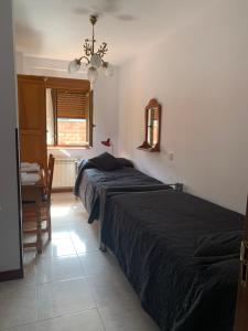 1 dormitorio con 2 camas, mesa y lámpara de araña en Apartamentos los Balcones, en Santander