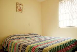 Un dormitorio con una cama con una manta de colores. en Casa Anillo vía, cerca a CC Cañaveral y Clínica, en Floridablanca
