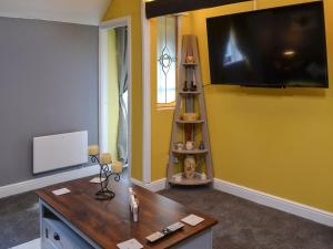 uma sala de estar com uma televisão de ecrã plano numa parede amarela em The Beehive em Miningsby