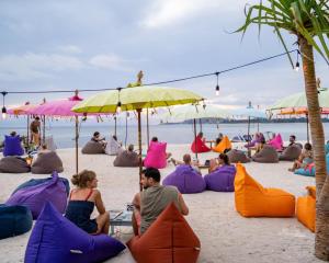 un grupo de personas sentadas en la playa bajo sombrillas en Gili Lumbung Bungalow, en Gili Air