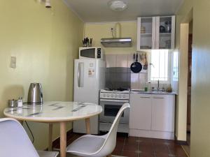 een kleine keuken met een tafel en een witte koelkast bij Loft cerca de playa in Viña del Mar