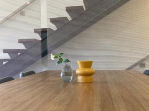 uma mesa de madeira com um vaso com uma flor em Byron Butter Factory Apartments em Byron Bay