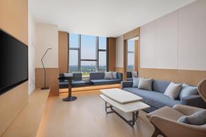 a living room with a couch and a tv at Fairfield by Marriott Liaocheng Dongchangfu in Liaocheng
