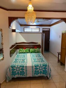 een slaapkamer met een bed en een kroonluchter bij Bellevue Raiatea in Uturoa