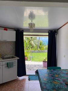 a room with a bed and a kitchen with a window at Bellevue Raiatea in Uturoa
