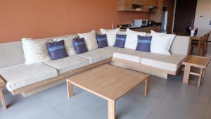 a large white couch with blue pillows and a table at Baan Chan Talay - D32 A modern comfortable 2 bedroom apartment in Chaam in Ban Bang Sai Yoi