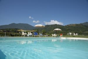 una grande piscina con sedie e ombrelloni di fronte alle montagne di Country House Case Di Stratola a Montella