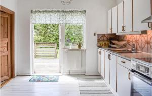 uma cozinha com armários brancos e uma porta aberta em Beautiful Home In Tomelila With Kitchen em Tomelilla