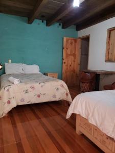 una camera da letto con due letti e pavimento in legno di Hotel Arcos del Carmen a San Cristóbal de Las Casas