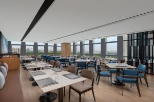 a restaurant with tables and chairs and windows at Fairfield by Marriott Liaocheng Dongchangfu in Liaocheng