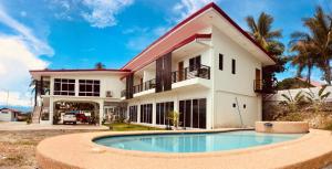 a house with a swimming pool in front of it at Elnora Delmar Travellers Inn in Siquijor