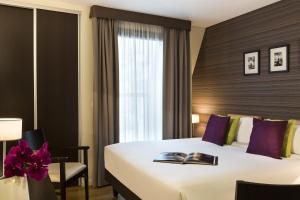 a hotel room with a bed with a book on it at Citadines République Paris in Paris