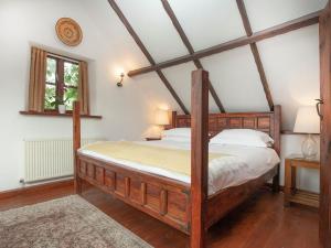 a bedroom with a wooden bed in a room at The Barn in Kentisbeare