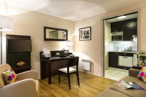 a living room with a desk and a kitchen at Citadines République Paris in Paris