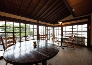 a large room with a table and chairs and windows at Ryokan Kiraku in Beppu