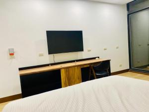 Zimmer mit einem Schreibtisch und einem TV an der Wand in der Unterkunft 浯島文旅WD Hotel in Jinhu