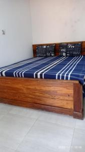 uma cama de madeira com um colchão listrado azul e branco em Green berg 