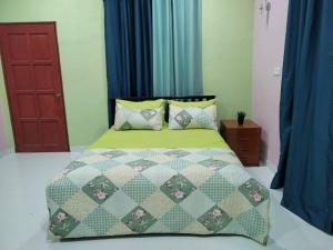 a bed with a green comforter and pillows in a bedroom at Inap Desa 1 in Kampong Siput
