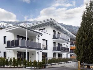 un edificio de apartamentos blanco con balcones y árboles en Zillertal Juwel, en Fügen