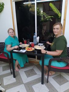 Dos mujeres sentadas en una mesa con comida. en Thoddoo Haisha inn, Maldives en Thoddoo