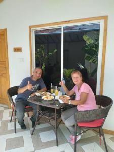 un hombre y una mujer sentados en una mesa comiendo comida en Thoddoo Haisha inn, Maldives en Thoddoo