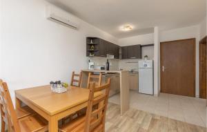 a kitchen and dining room with a table and a refrigerator at Cozy Apartment In Njivice With Kitchen in Njivice