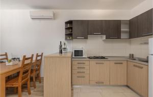 a kitchen with wooden cabinets and a table with chairs at Cozy Apartment In Njivice With Kitchen in Njivice