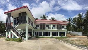 a large white building with a red roof at Elnora Delmar Travellers Inn in Siquijor