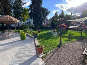 a garden with tables and chairs and an umbrella at Hôtel Le Manoir in Barr +66 photos