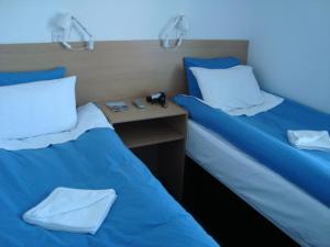 2 bedden in een kamer met blauwe lakens en witte kussens bij Hostel Alma in Dover