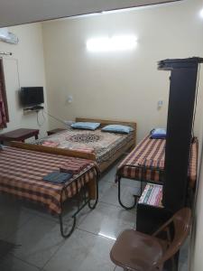 a room with two beds and a chair in it at Suloram illam in Chidambaram