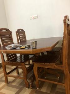 mesa de comedor de madera con 2 sillas y mesa en ASP COTTAGE, en Tenkāsi
