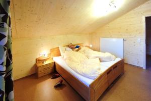 a person laying in a bed in a wooden room at Feriendorf am Hahnenkamm in Reutte