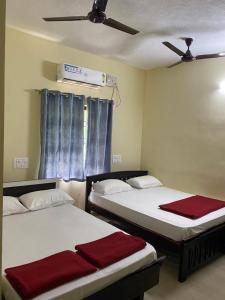 two beds in a room with a ceiling fan at Adheesh Lodge in Dharmastala