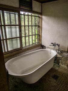 a large white bath tub in a room with windows at 竜野園藝 in Kamimashiki