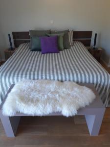 a bed with a white furry cushion on it at B&B Het Lavershuis in Wemmel