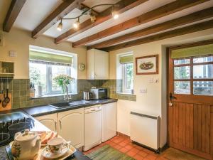 uma cozinha com um fogão, um micro-ondas e uma porta em Curlew Cottage em Bromlow