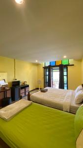two beds in a room with a green blanket on them at ภูคำฮ้อมคลิฟฟ์ลอดจ์ แอนด์ โฮมสเตย์ Phu come home cliff Lodge & Homestay in Ban Phu Hi