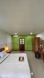 1 dormitorio con 1 cama blanca grande y paredes verdes en ภูคำฮ้อมคลิฟฟ์ลอดจ์ แอนด์ โฮมสเตย์ Phu come home cliff Lodge & Homestay, en Ban Phu Hi