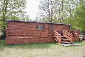 a large wooden cabin with a deck in the grass at Wilimy Domek przy plaży jeziora Dadaj in Biskupiec