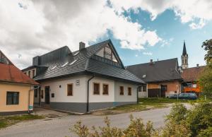 ein weißes Haus mit schwarzem Dach und einer Kirche in der Unterkunft Privat LeNa in Ružomberok