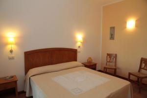 a bedroom with a bed with two chairs and two lights at Agriturismo La Ronca in San Vincenzo +11 photos
