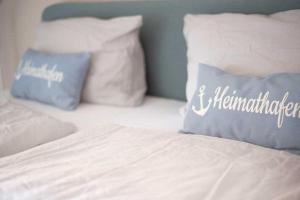 Bett mit weißer Bettwäsche und blauen Kissen in der Unterkunft Schiller-Quartier 6 in Bremerhaven