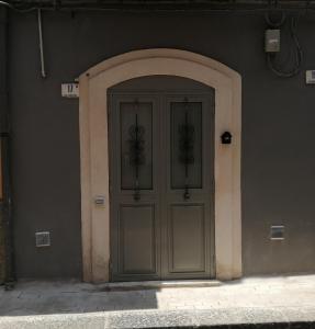 une porte menant à un bâtiment avec une arche autour de lui dans l'établissement Dimora Genovesi, à Catane