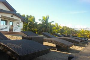 a row of wicker chairs sitting on the beach at Goichi Resort in Dipaculao