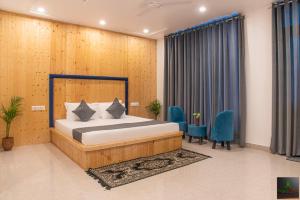 a bedroom with a bed and some blue chairs at The Cloud berry I Property of the year I Serviced Villa I Couple Friendly I Pvt Balcony I Open Air Terrace I Bonfire I Kasauli By Exotic Stays in Kasauli