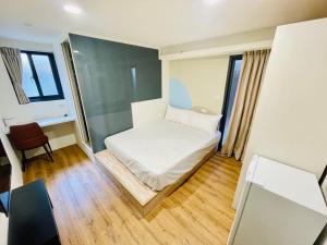 um pequeno quarto com uma cama e uma cadeira em 樂萄萄逢甲 em Taichung