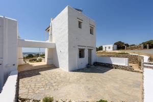 a white house with a stone walkway in front of it at Parian Philoxenia Villa, Santa Maria Beach in Kampos Paros